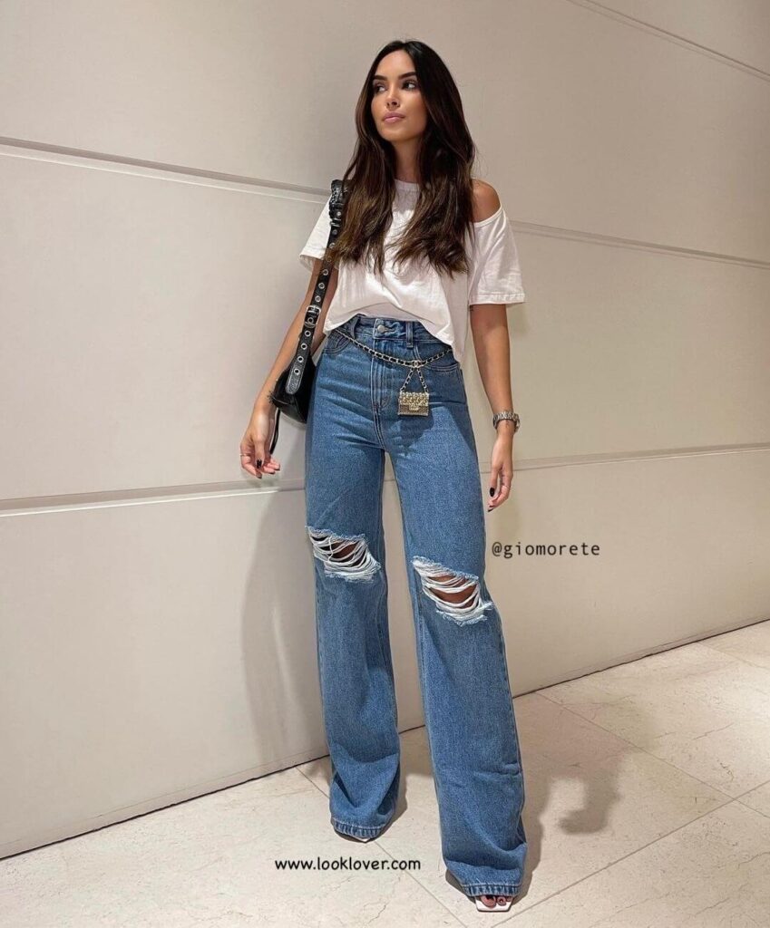 look com calça jeans destroyed com boca larga, blusa branca, bolsa preta e rasteirinha